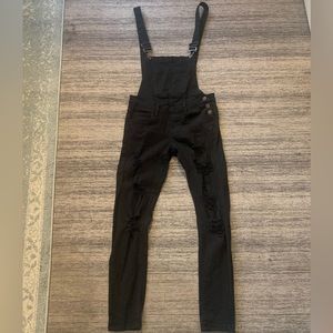 Black jeans skinny overalls with distressed holes in both knees.